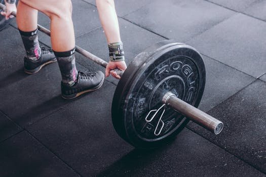 Focused shot of a person lifting a barbell, highlighting strength and fitness. visitante