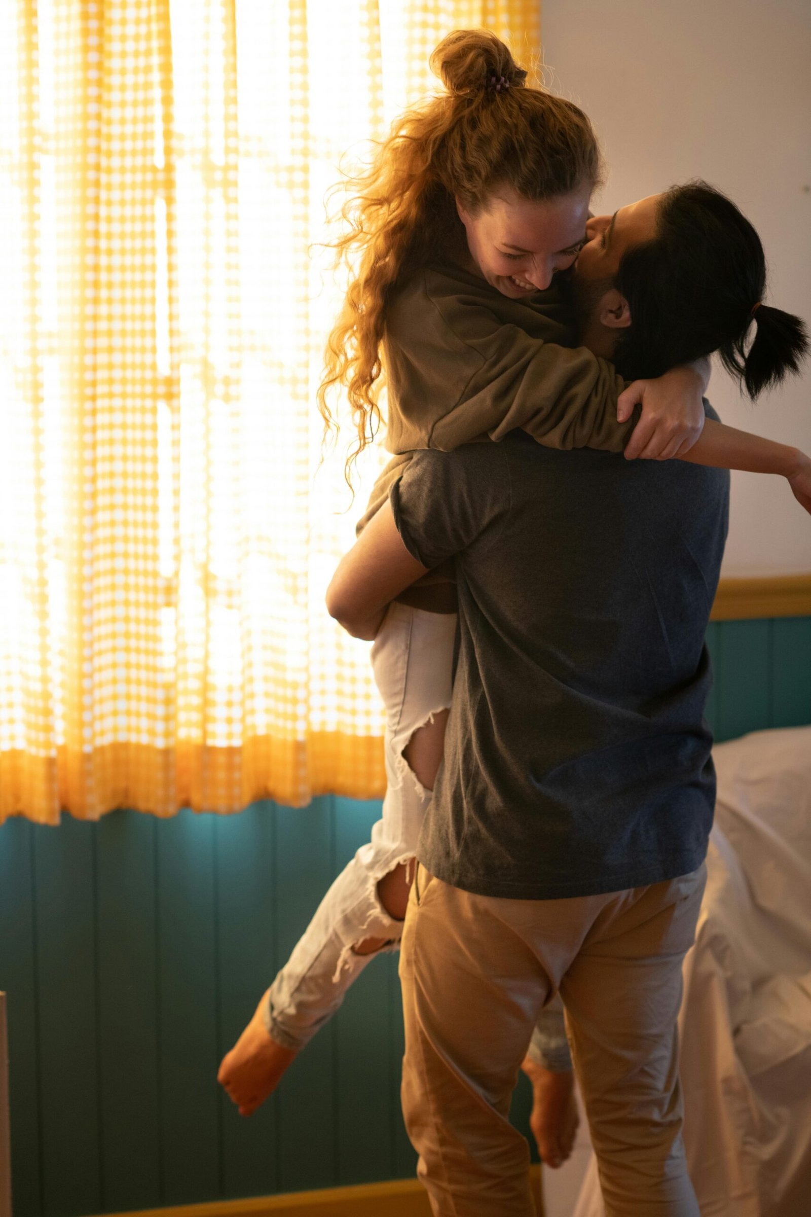 Joyful moment of a couple hugging in their cozy, sunlit living room.