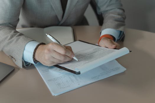 Close-up of business person signing documents at a desk with a pen. avcb