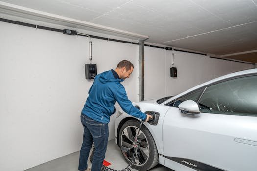 A man connects an electric car to a charging station in a modern indoor garage setting. elétrico