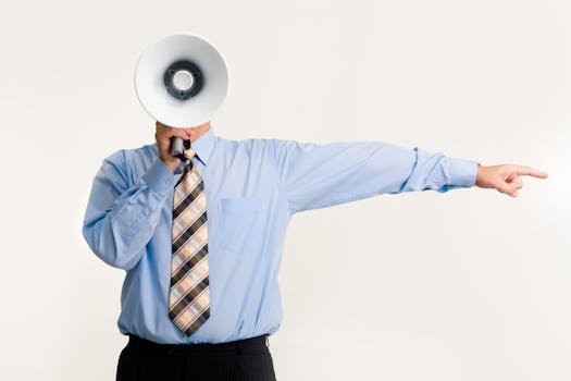 Businessman in blue shirt using a megaphone while pointing, isolated on white background. abuso