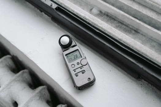 A close-up of a digital light meter placed on a windowsill, emphasizing modern photo equipment. barulho