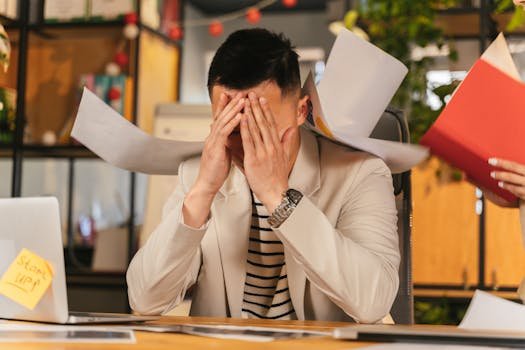 Stressed businessman overwhelmed by paperwork in office environment, demonstrating burnout. horario