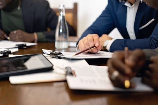 Business meeting with adults discussing and signing contracts over a table. seguro