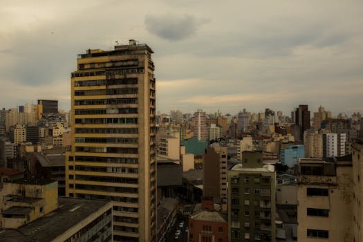 Aerial view of a cloudy urban skyline featuring diverse types of high-rise buildings. inadimplência
