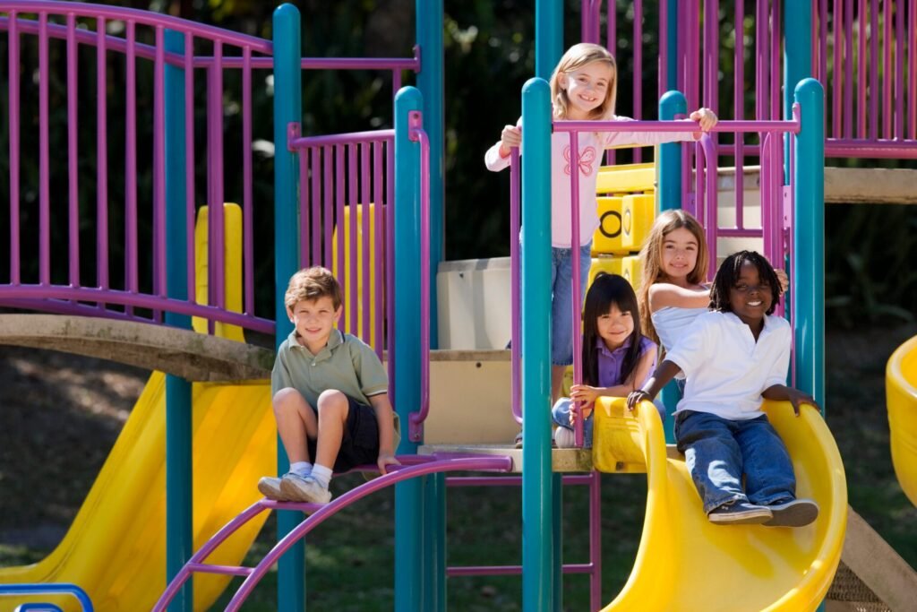A group of diverse children enjoying playground slides on a sunny day outdoors.