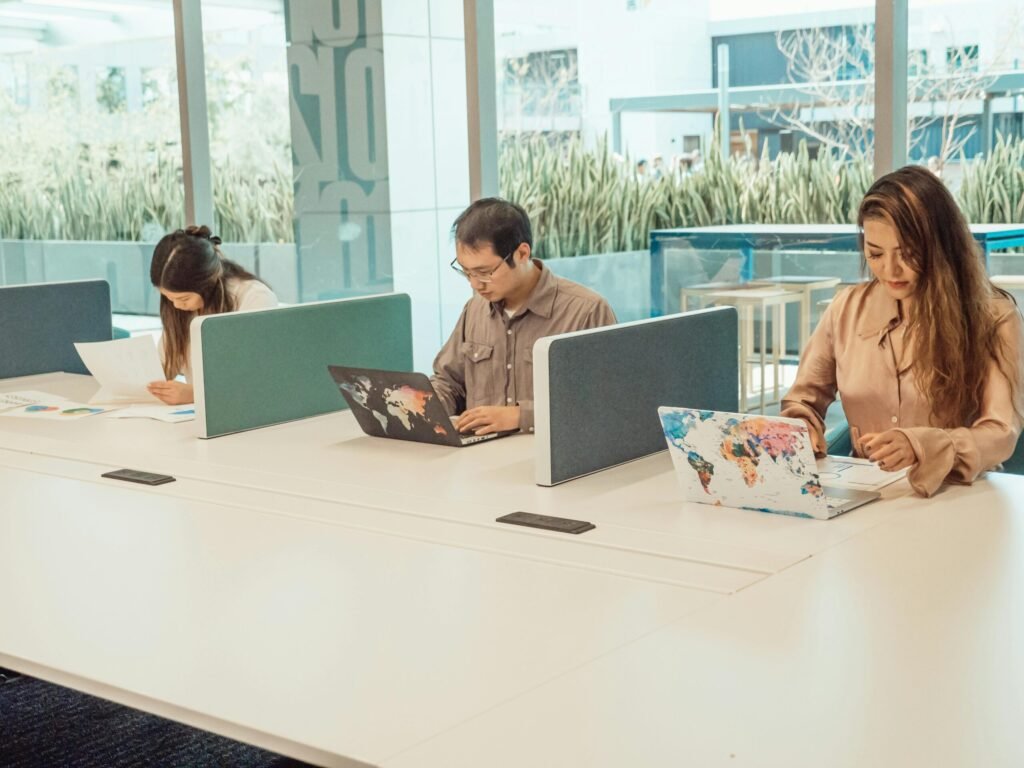 Group of diverse employees working in a contemporary open office with laptops and documents.